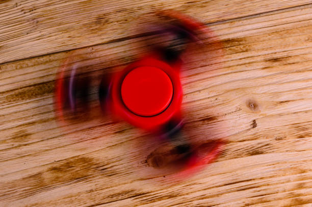 istock Red fidget spinner rotates on wooden desk 821722938