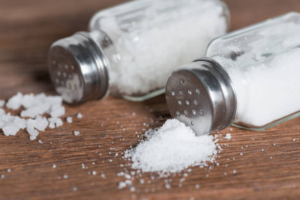 istock Salt in salt shaker on dark wood background. 821728008