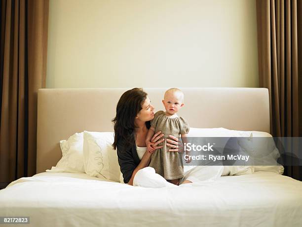 Mother And Daughter Sitting On Bed Stock Photo - Download Image Now - Family, Wealth, Baby - Human Age