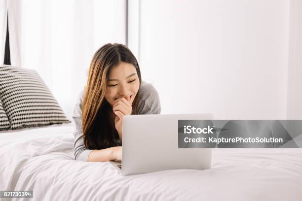 Young Asian Girl Using Laptop On The Bed Stock Photo - Download Image Now - Laptop, Bed - Furniture, Japanese Ethnicity