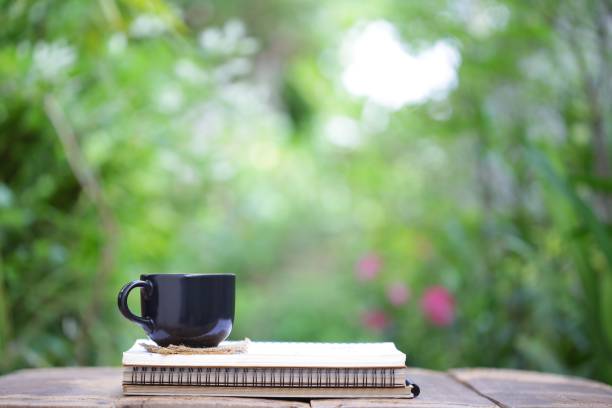 istock Notebook  and coffee in black cup on wooden table 821731240