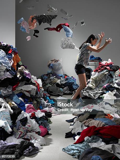 Woman Throwing Clothes In Overflowing Laundry Room Stock Photo - Download Image Now - Messy, Cluttered, Domestic Life