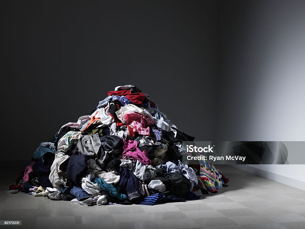 Large pile of clothes in an empty room.  Clothing Stock Photo