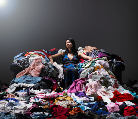 Mujer sentada en el sofá, rodeado de prendas. photo