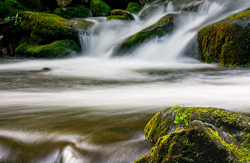 small cascades on the forest river among huge bouders covered with moss. taken with long exposure. beautiful fresh nature background