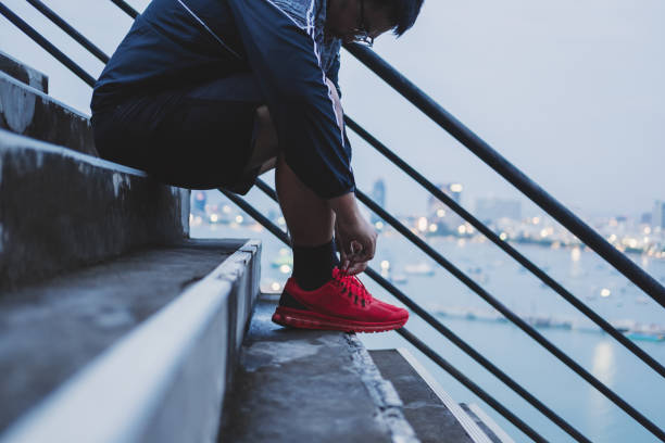 asian guy tying running shoe, prepararsi a correre per la dieta, allenarsi per perdere peso - weight scale dieting weight loss foto e immagini stock