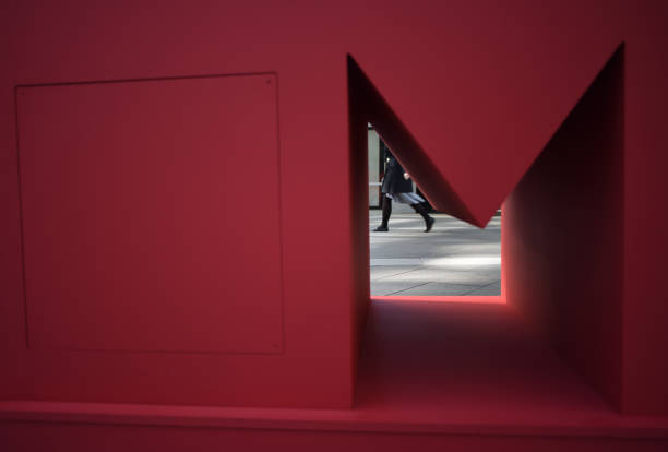 Woman walking seen through a block with Letter M. Conceptual image for Capital cities such as Melbourne, Milan or Mexico. Shopping districts.This is an image of a block of letters put up by local shopping centre to promote Milan as a shopping and travel destination. The image is a close up on one of the letters. It is not a work of art.