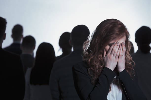 Young woman covering her face and crying standing back to back with a crowd