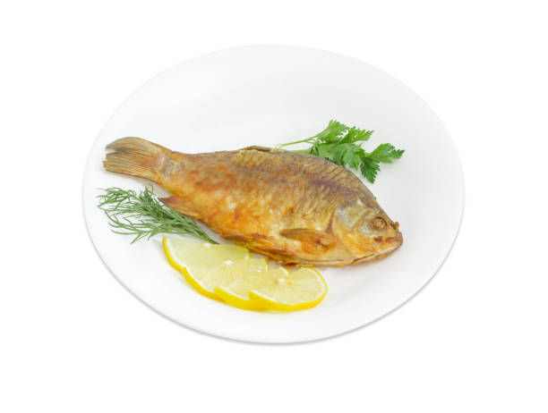 istock Fried crucian with lemon and potherb on white dish 821760212
