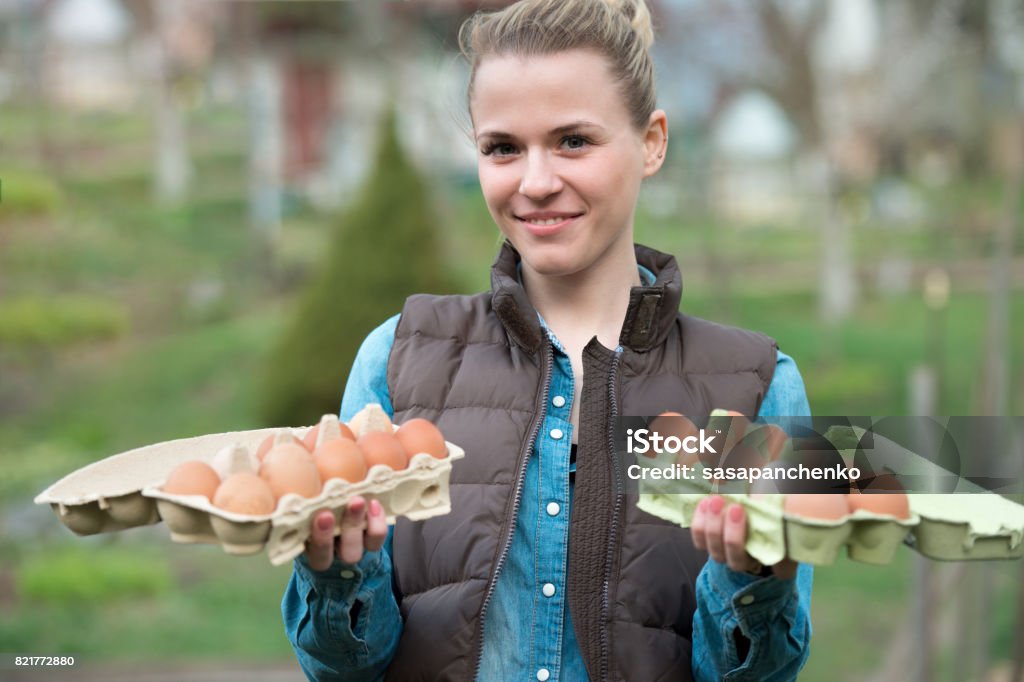 A Woman Gathering Fresh Eggs Into Basket At Hen Farm In