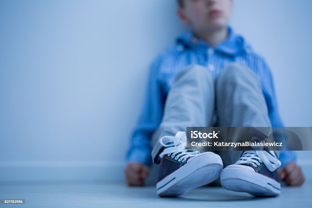 Boy sitting on a floor Sad boy sitting on a floor in a room Child Stock Photo