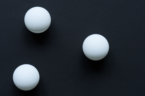 Three white balls scattering on black surface