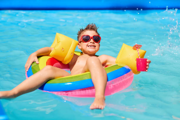 niño feliz en gafas de sol en la piscina con un coctel. - child swimming pool swimming little boys fotografías e imágenes de stock