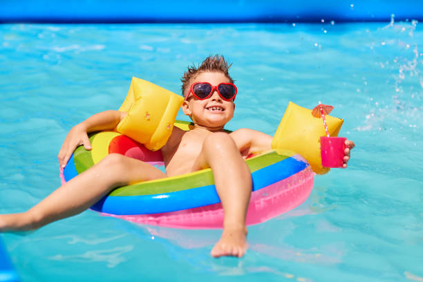 bambino felice con occhiali da sole in piscina con un cocktail. - child swimming pool swimming little boys foto e immagini stock