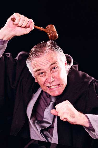 istock Furious judge, fist clenched, waving gavel and grimacing 821786438