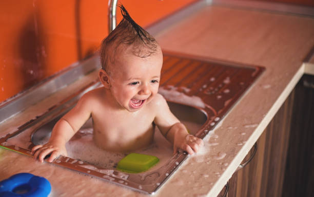 istock Baby boy in kitchen sink full water and foam 821787224