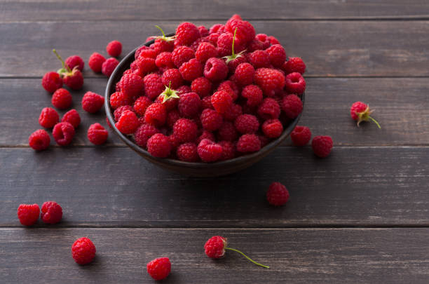 istock Red fresh raspberries on brown rustic wood background 821787950
