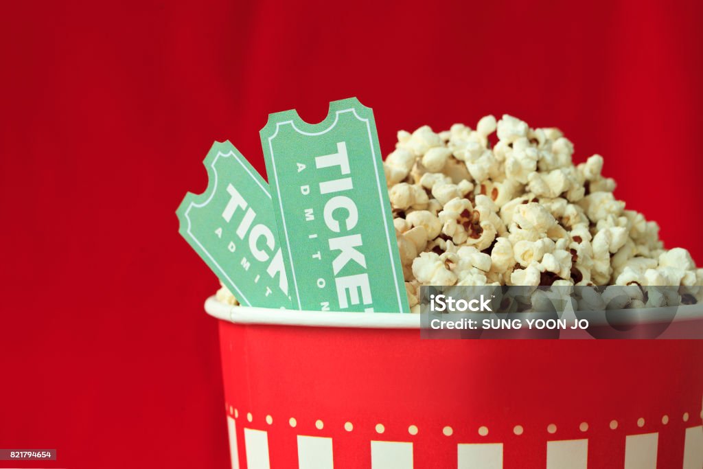 Borsa popcorn e biglietto del film su sfondo rosso - Foto stock royalty-free di Biglietto del cinema