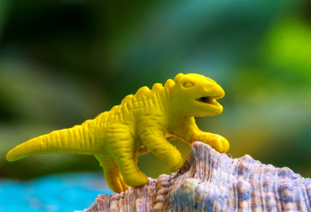 istock Yellow toy dinosaur on natural shell. Small puppet macro photo. 821795684