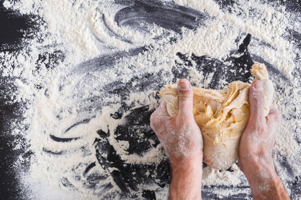 istock Hands top view knead dough on black background 821799052