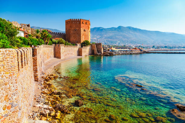 Kizil Kule tower in Alanya peninsula, Antalya district, Turkey, Asia. Famous tourist destination with high mountains. Part of ancient old Castle. Summer bright day Kizil Kule tower in Alanya peninsula, Antalya district, Turkey, Asia. Famous tourist destination with high mountains. Part of ancient old Castle. Summer bright day antalya province photos stock pictures, royalty-free photos & images
