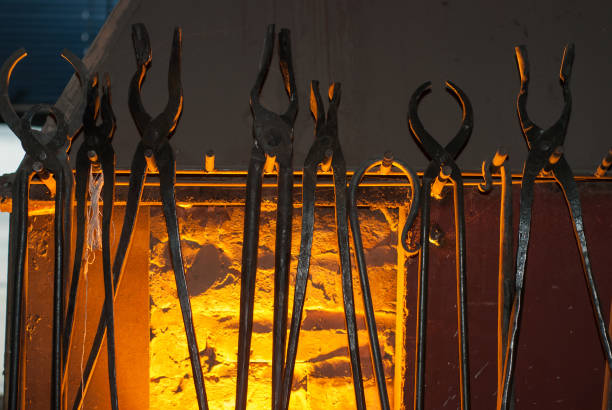 Set of old blacksmith tongs closeup, against horn, the light from the fire