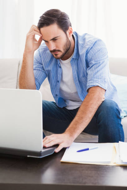 istock Worried man sitting at table using laptop to pay his bills 821812234
