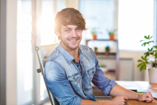 istock Smiling casual businessman sitting at desk 821814836