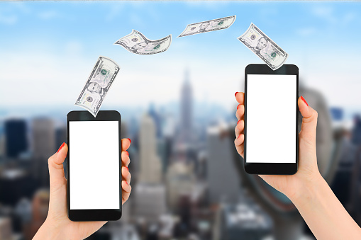 Mobile payment or money transfer with smartphone, Empire State Building and Financial District as blur background