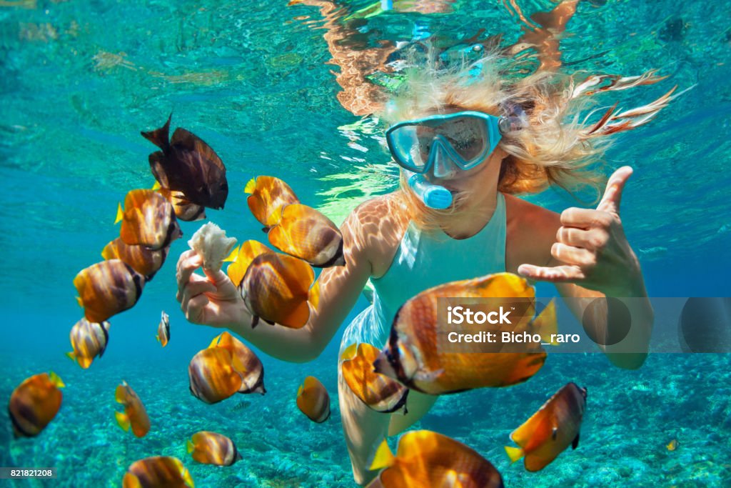 Mujer joven snorkeling con peces de arrecife de coral - Foto de stock de Buceo con tubo libre de derechos