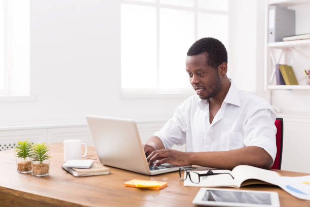 istock Black happy businessman in white office, work with laptop 821824614