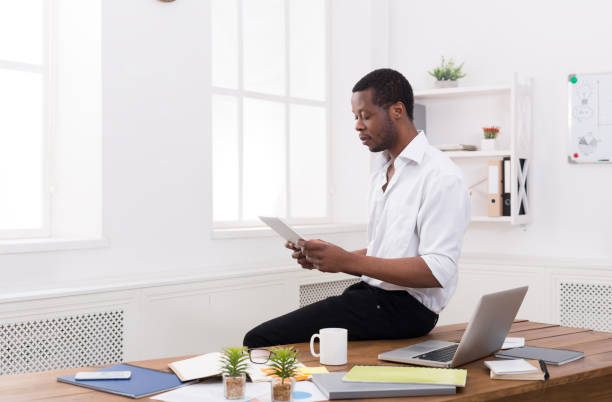 istock Concentrated black businessman in modern office, work with tablet 821825742