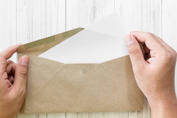istock Hand hold a envelope and paper on the wooden background 821825846