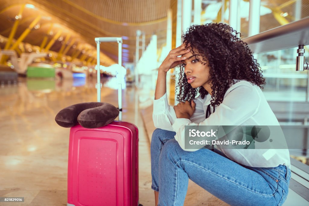 black Woman upset and frustrated at the airport with flight canceled Woman sad and unhappy at the airport with flight canceled Airport Stock Photo