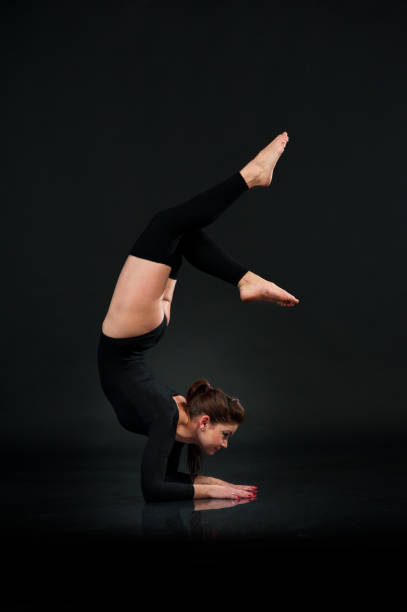 istock Sporty gymnastics woman on black background stretching doing Hands Standing Upside Down 821829428