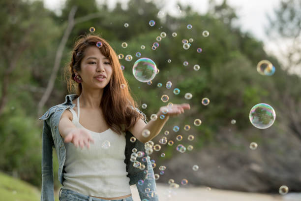 istock Young female having fun and blowing bubbles outdoors 821832460