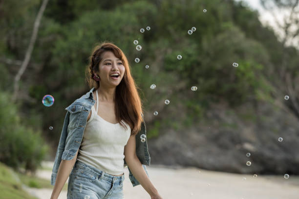 istock Young female having fun and blowing bubbles outdoors 821832468