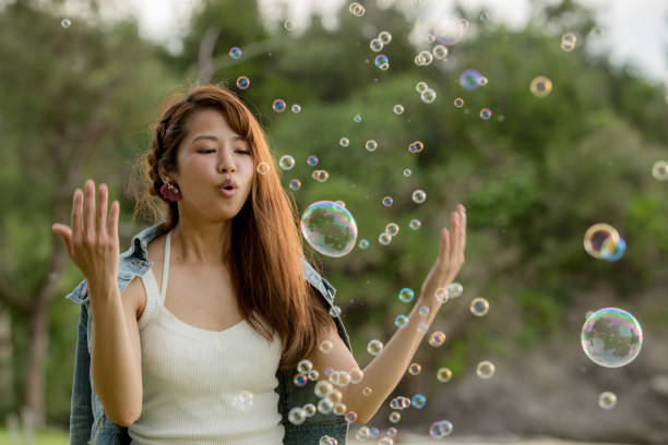 istock Young female having fun and blowing bubbles outdoors 821832496
