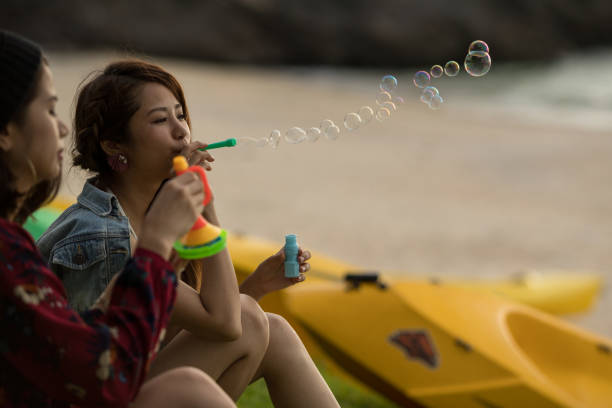 istock Young female having fun and blowing bubbles outdoors 821832600