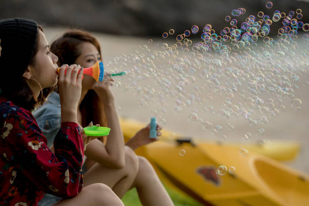 istock Young female having fun and blowing bubbles outdoors 821832602
