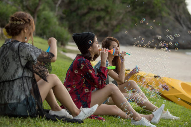 istock Young female having fun and blowing bubbles outdoors 821832606