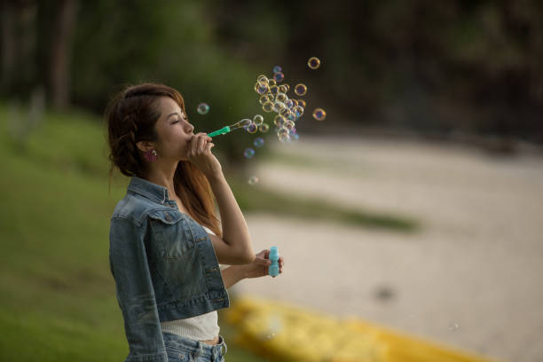 istock Young female having fun and blowing bubbles outdoors 821832722