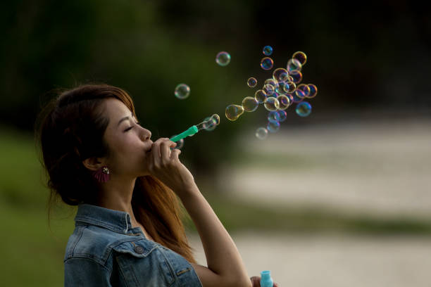 istock Young female having fun and blowing bubbles outdoors 821832728