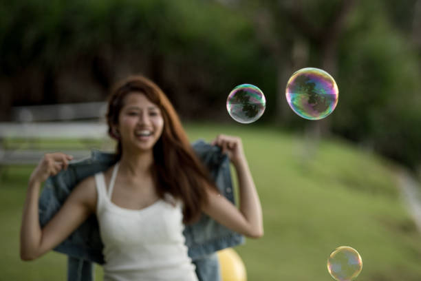 istock Young female having fun and blowing bubbles outdoors 821832734