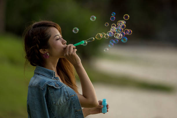 Young female having fun and blowing bubbles outdoors.