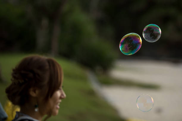 istock Young female having fun and blowing bubbles outdoors 821832748
