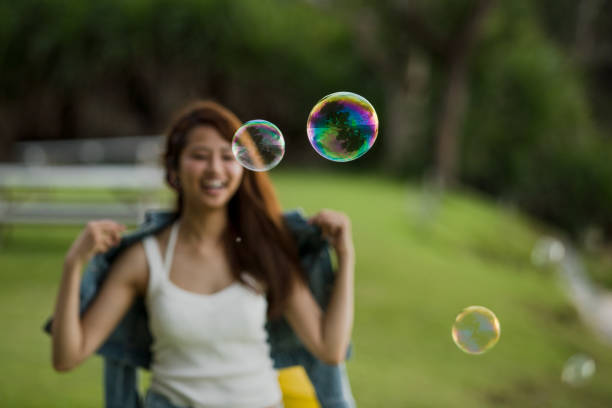 Young female having fun and blowing bubbles outdoors
