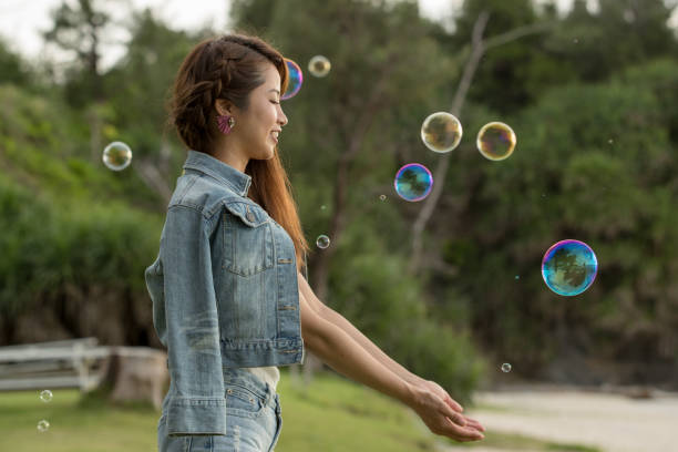 istock Young female having fun and blowing bubbles outdoors 821832764