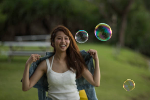 istock Young female having fun and blowing bubbles outdoors 821832766