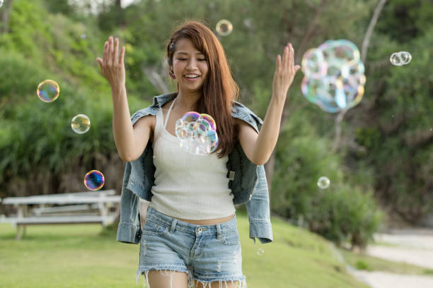 istock Young female having fun and blowing bubbles outdoors 821832774